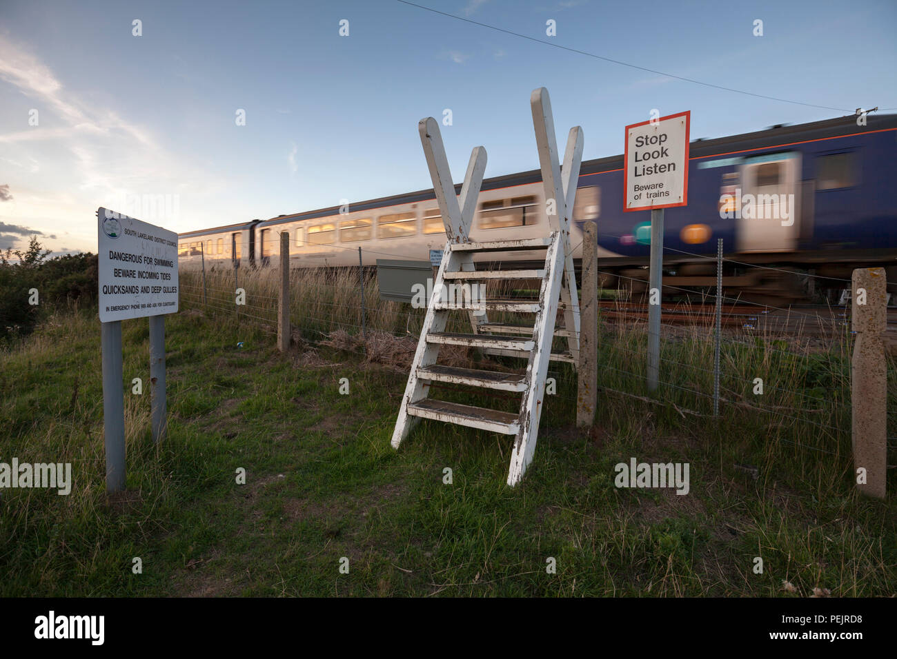 Eine nördliche Bahn Klasse 156 Sprinter Zug passiert den öffentlichen Fuß Überfahrt über die Bahnstrecke Kirkby In Furness mit Stop look Listen unterschreiben. Stockfoto