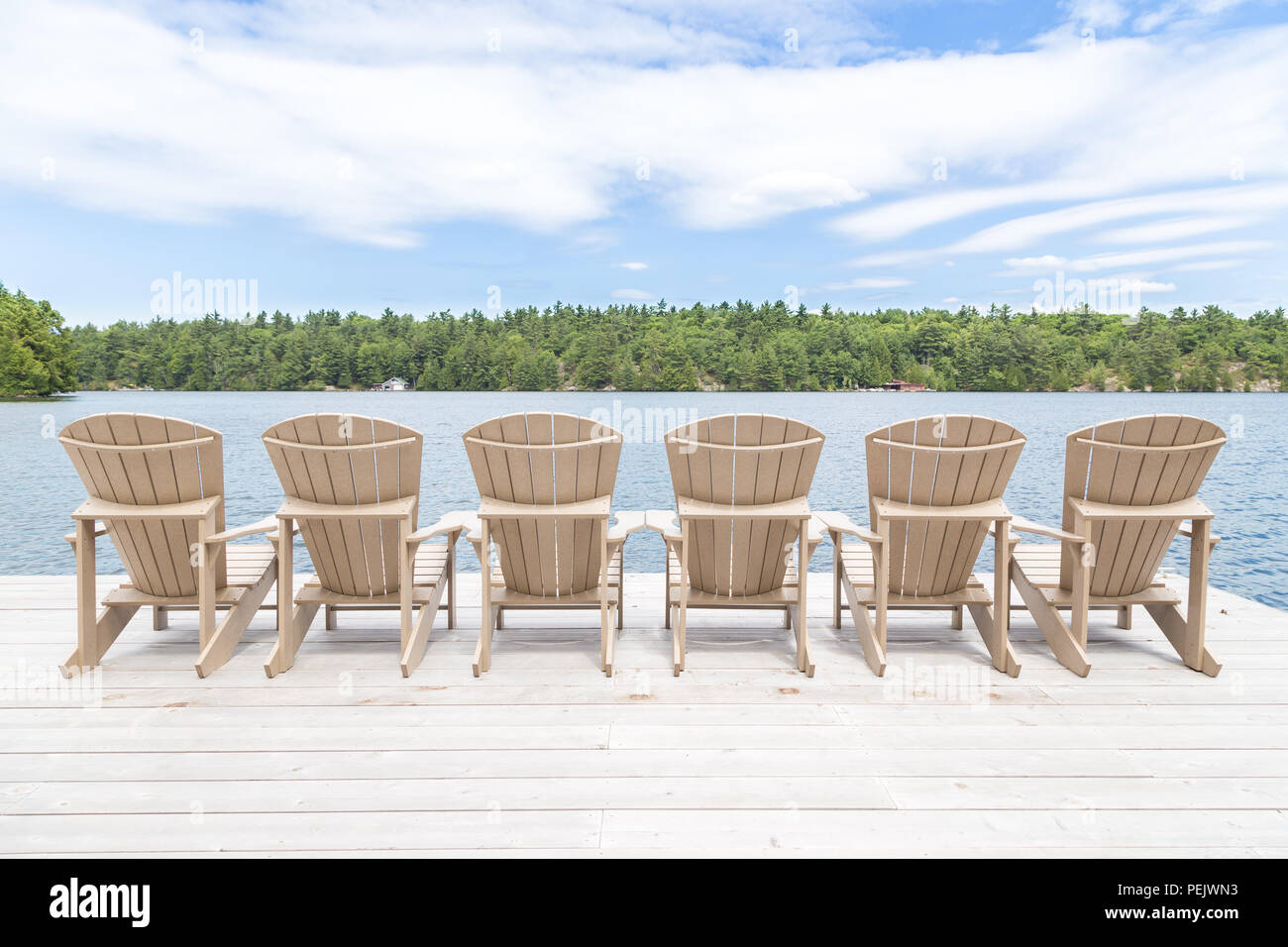 Reihe von Muskoka Stühle auf ein Dock mit Blick auf den See. Stockfoto