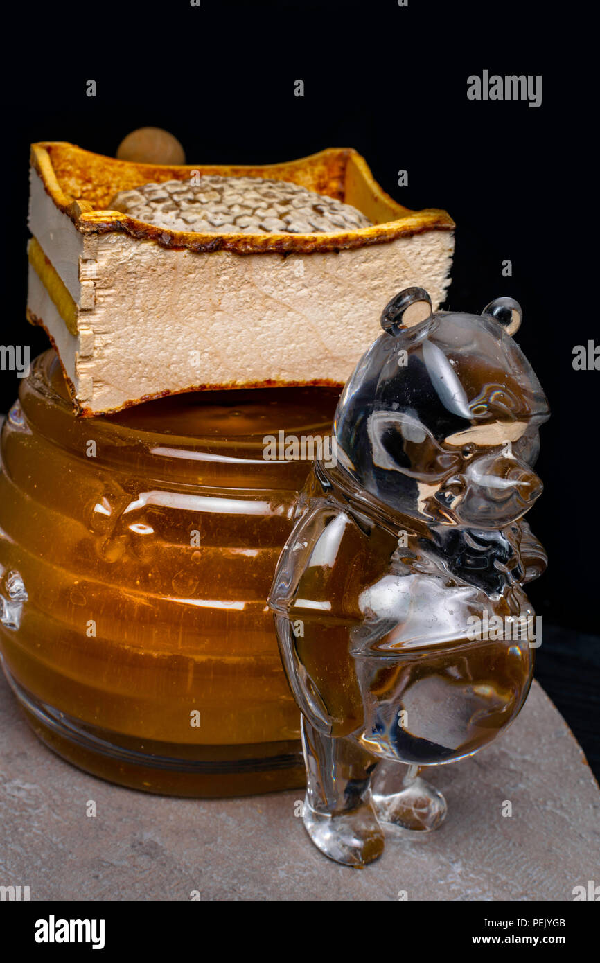 Honig im Glas container wie ein Bär und Honigseim, Holzstab geformt Stockfoto