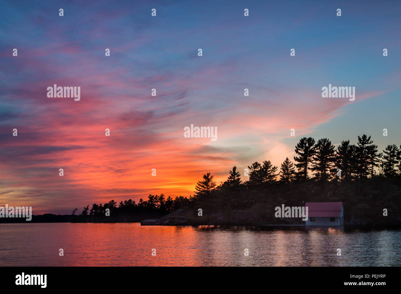 Kleines Häuschen im Schatten auf einem See bei Sonnenuntergang. Stockfoto