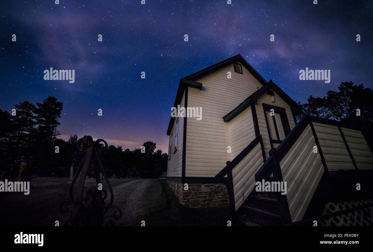 Ein Land Kirche neben einem Friedhof bei Nacht. Stockfoto