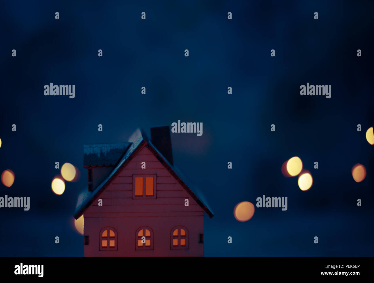 Miniatur Christmas Village Szene mit Spielzeug Holz- haus Fenster beleuchtet mit gelbem Licht mit dunkelblauen Hintergrund. Grußkarte Konzept. Stockfoto