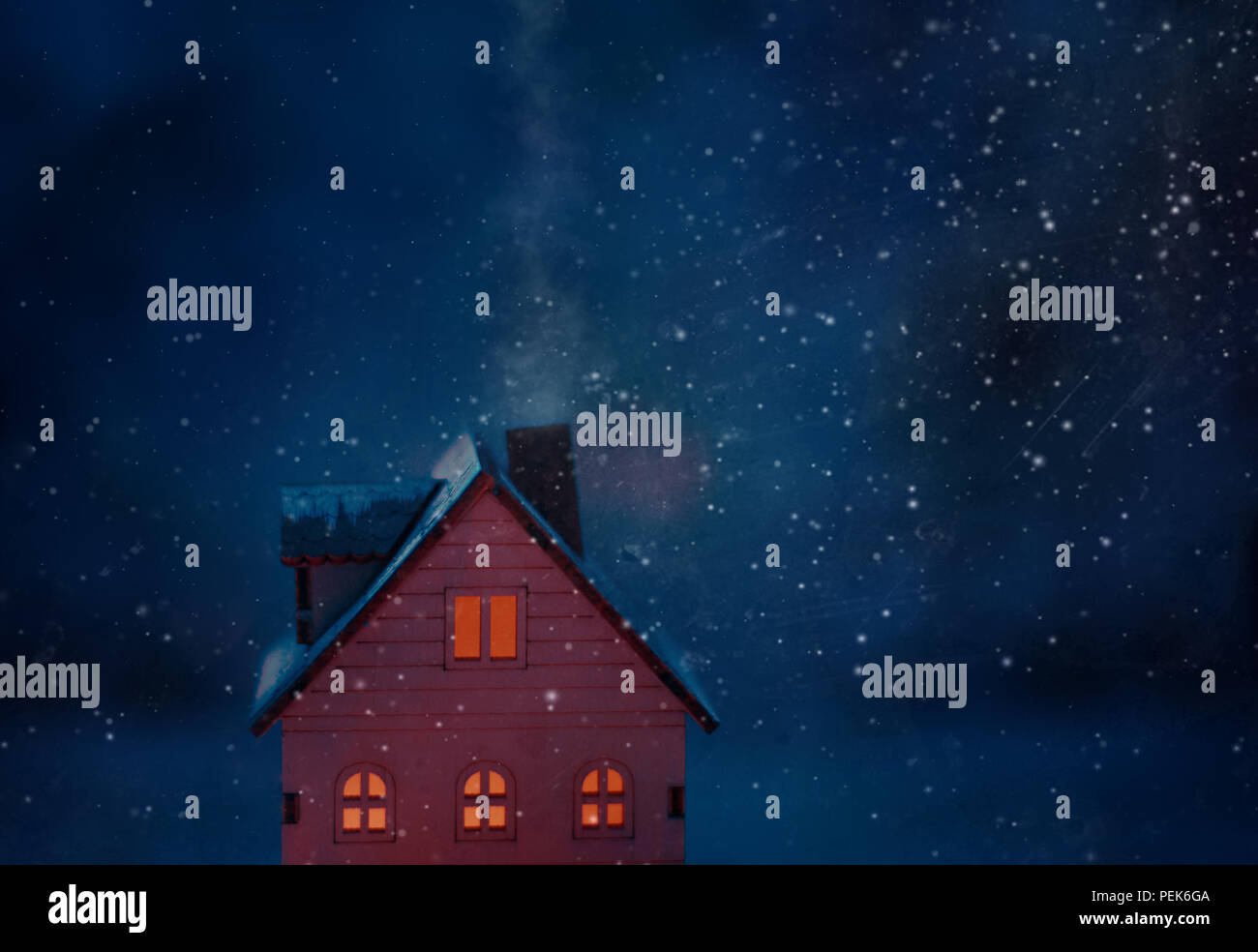 Miniatur Christmas Village Szene mit Spielzeug Holz- haus Fenster beleuchtet mit gelbem Licht mit dunkelblauen Hintergrund, Rauch aus dem Schornstein und Schnee Stockfoto