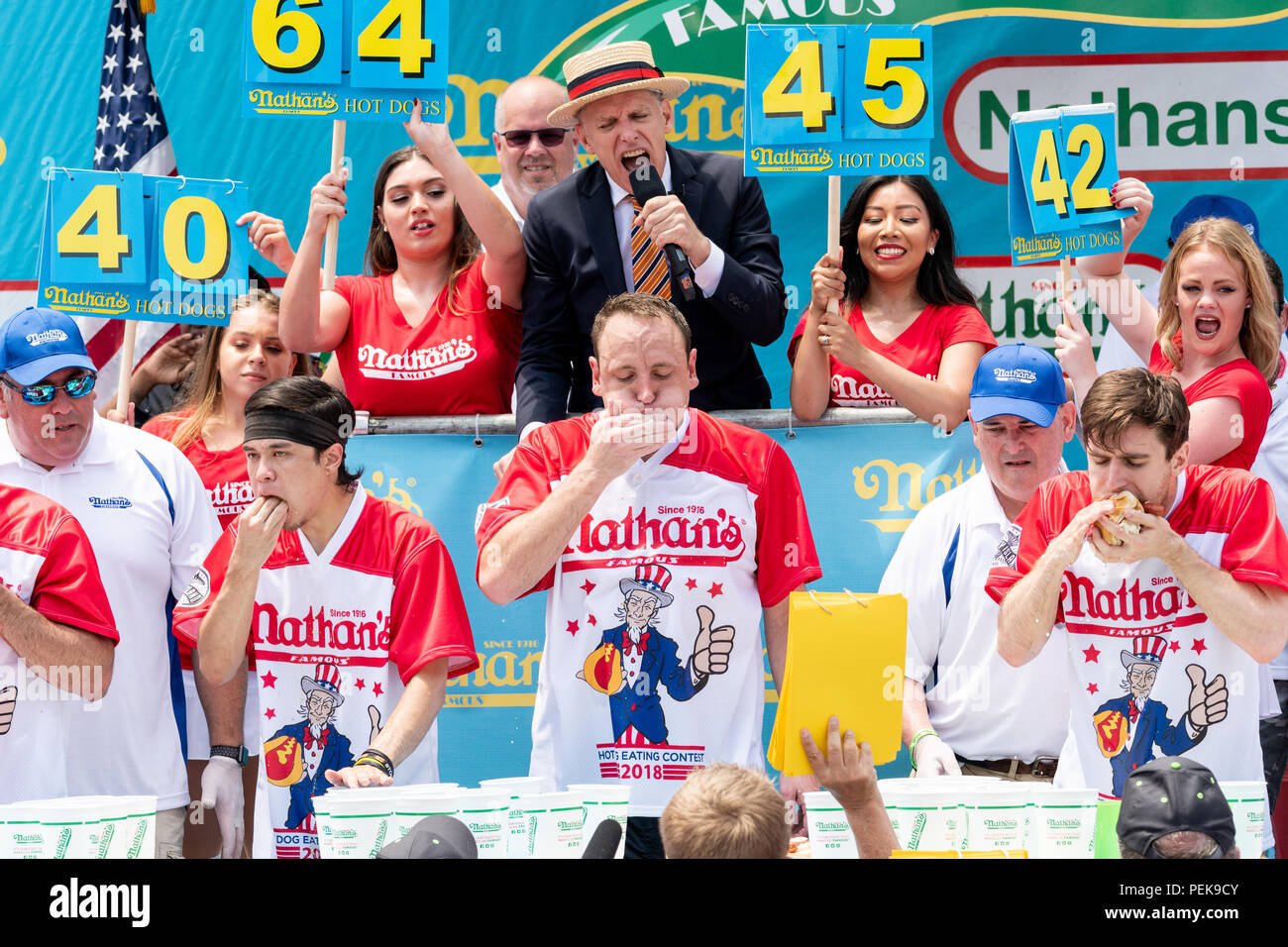 Joey Chestnut (Mitte, gerade unter den Menschen im Stroh Hut und blauen Blazer) gegessen und Brötchen 74 Hot Dogs in zehn Minuten einen neuen Weltrekord, der 2018 Na win Stockfoto