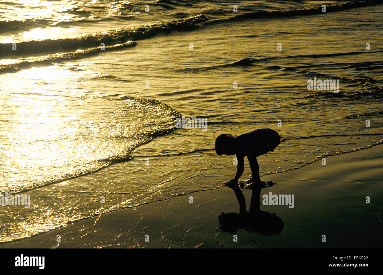 Kleine Mädchen spielen am Strand bei Sonnenuntergang Stockfoto