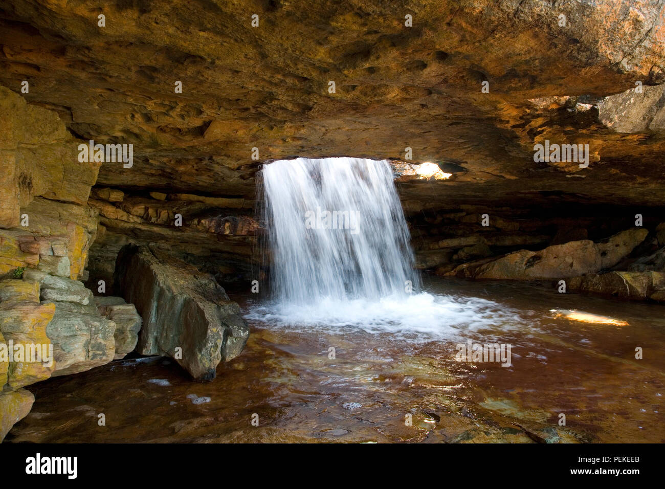 Das Wasser fällt durch das Loch im Felsen Stockfoto
