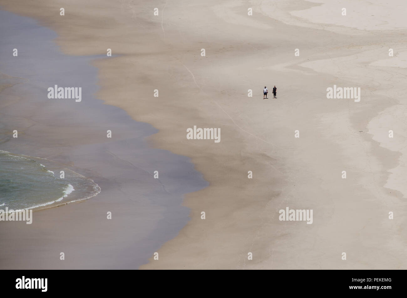 Zwei Menschen laufen entlang der Wasser auf leeren Strand, Tallow Beach, Byron Bay, New South Wales, Australien. Paare friedliche Einsamkeit auf einsamen Strand. Stockfoto