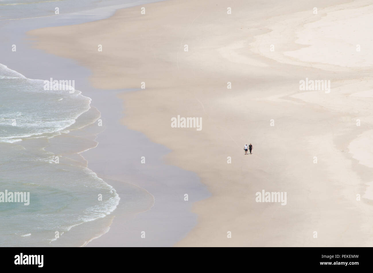 Zwei Menschen laufen entlang der Wasser auf leeren Strand, Tallow Beach, Byron Bay, New South Wales, Australien. Paare friedliche Einsamkeit auf einsamen Strand. Stockfoto