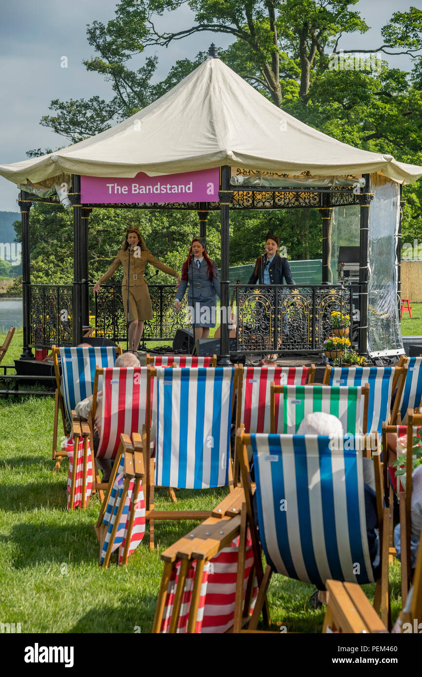 Publikum in Liegestühlen beobachten Musik am Musikpavillon durch die Gruppe von 3 Sängerinnen (Trio) - RHS Chatsworth Flower Show, Derbyshire, England, Großbritannien Stockfoto