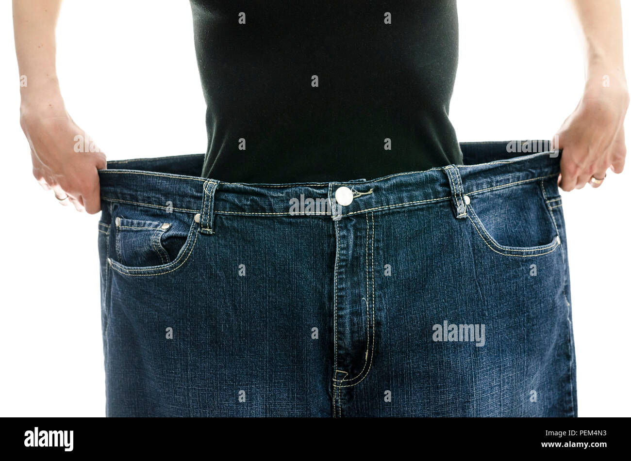 Frau zeigen, wie viel Gewicht Sie durch das Tragen Ihre alte Jeans verloren. Weightloss Konzept. Stockfoto