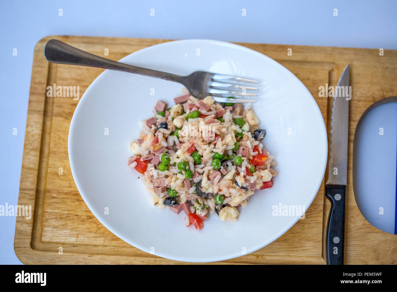 Italienische Reis Salat oder kalten Reis in eine weiße Platte auf einem Schneidebrett mit Messer und Gabel. Stockfoto