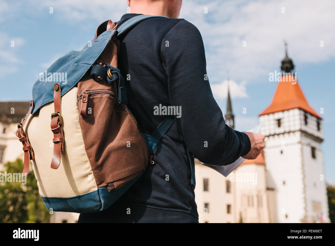 Ein Mann hält eine Karte in der Hand und sieht für Sehenswürdigkeiten. Die Burg namens Blatna in der Tschechischen Republik ist unscharf im Hintergrund. Urlaub, Reisen Stockfoto