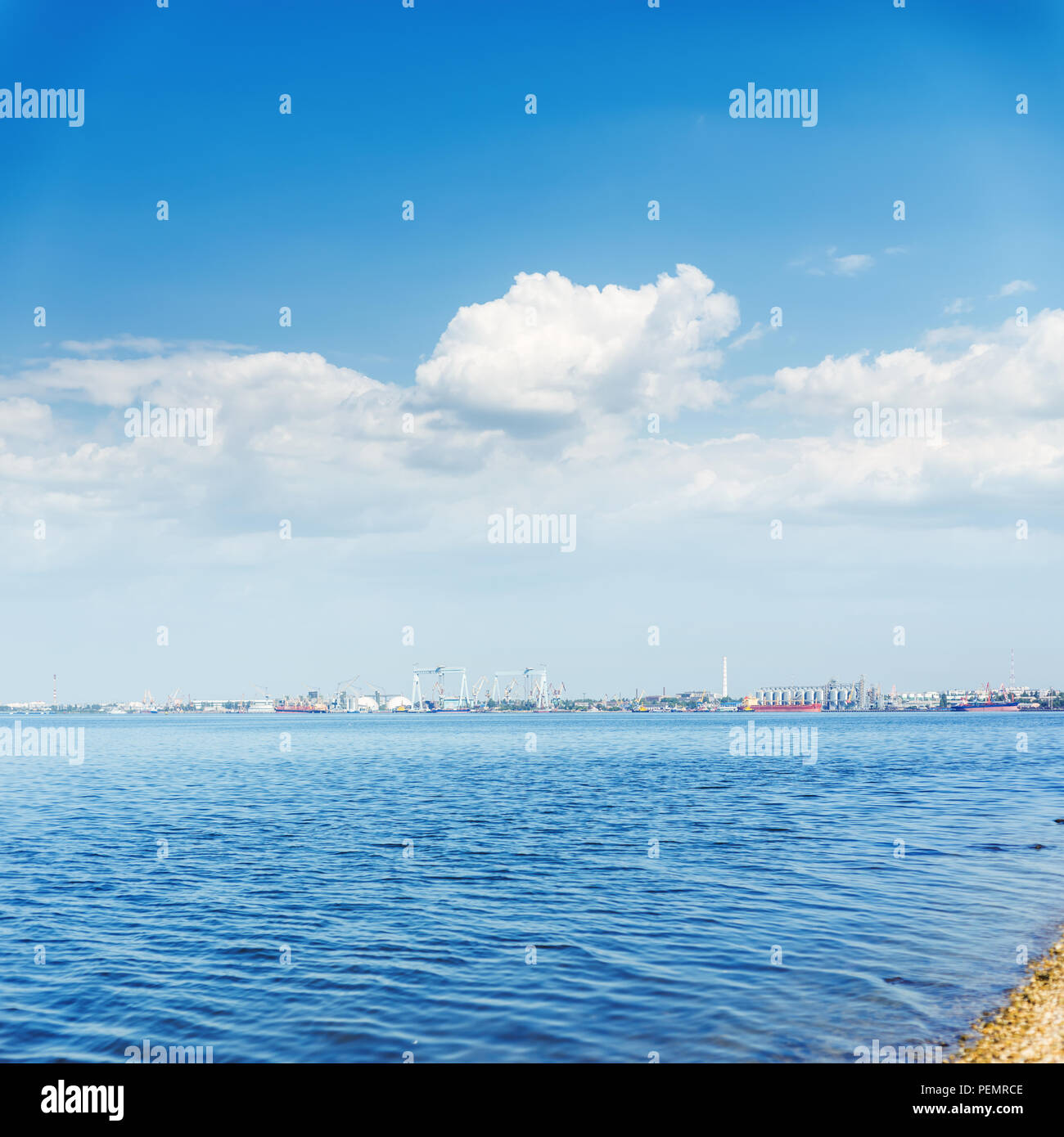 Big River und Wolken im blauen Himmel. Industrielle Horizont mit Schiffbau und Aufbewahrungsboxen Stockfoto