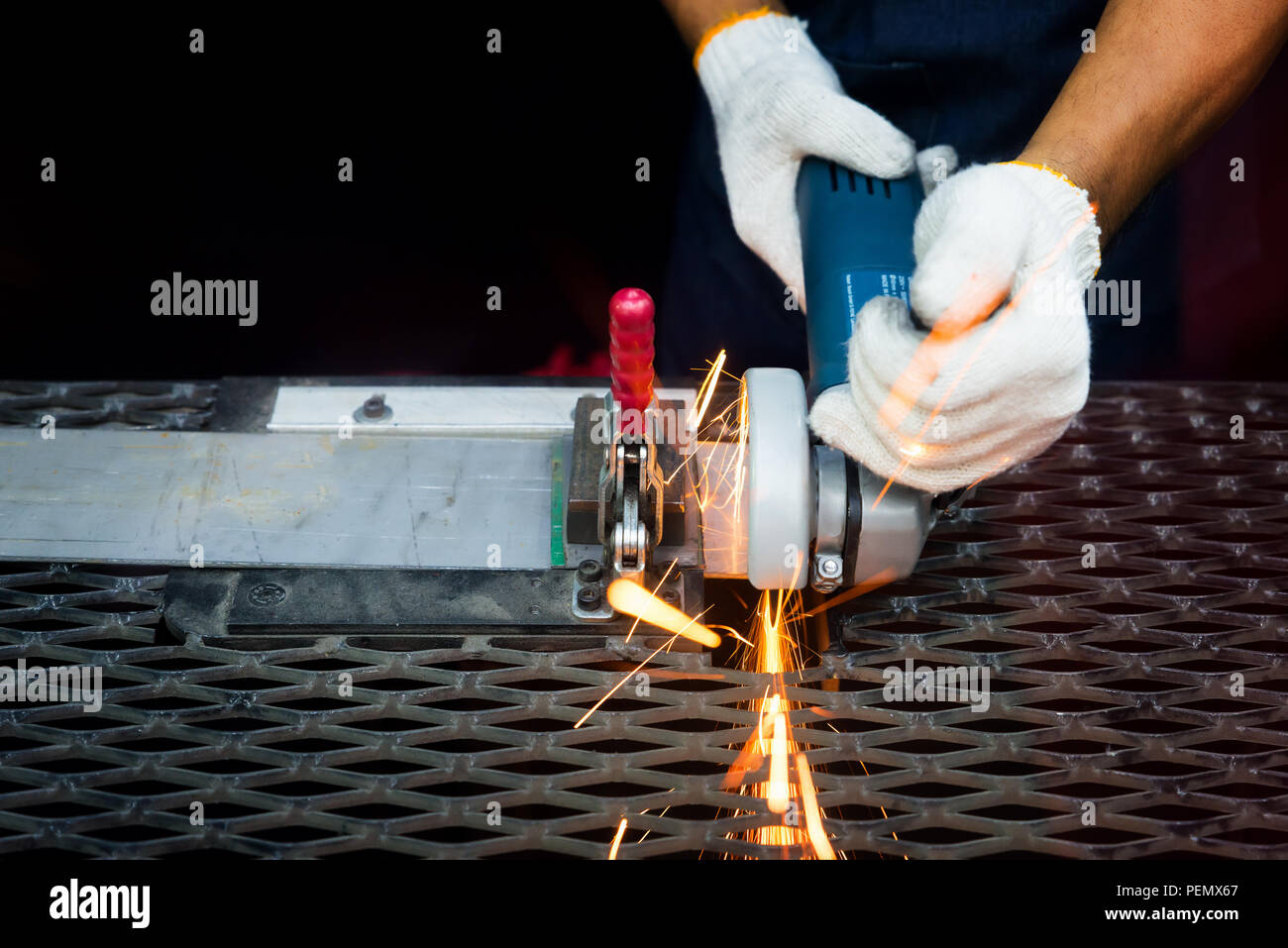 Arbeiter mit Mahlwerk schneiden und Schweißen von Metall mit vielen scharfen Funken in Fabrik Stockfoto