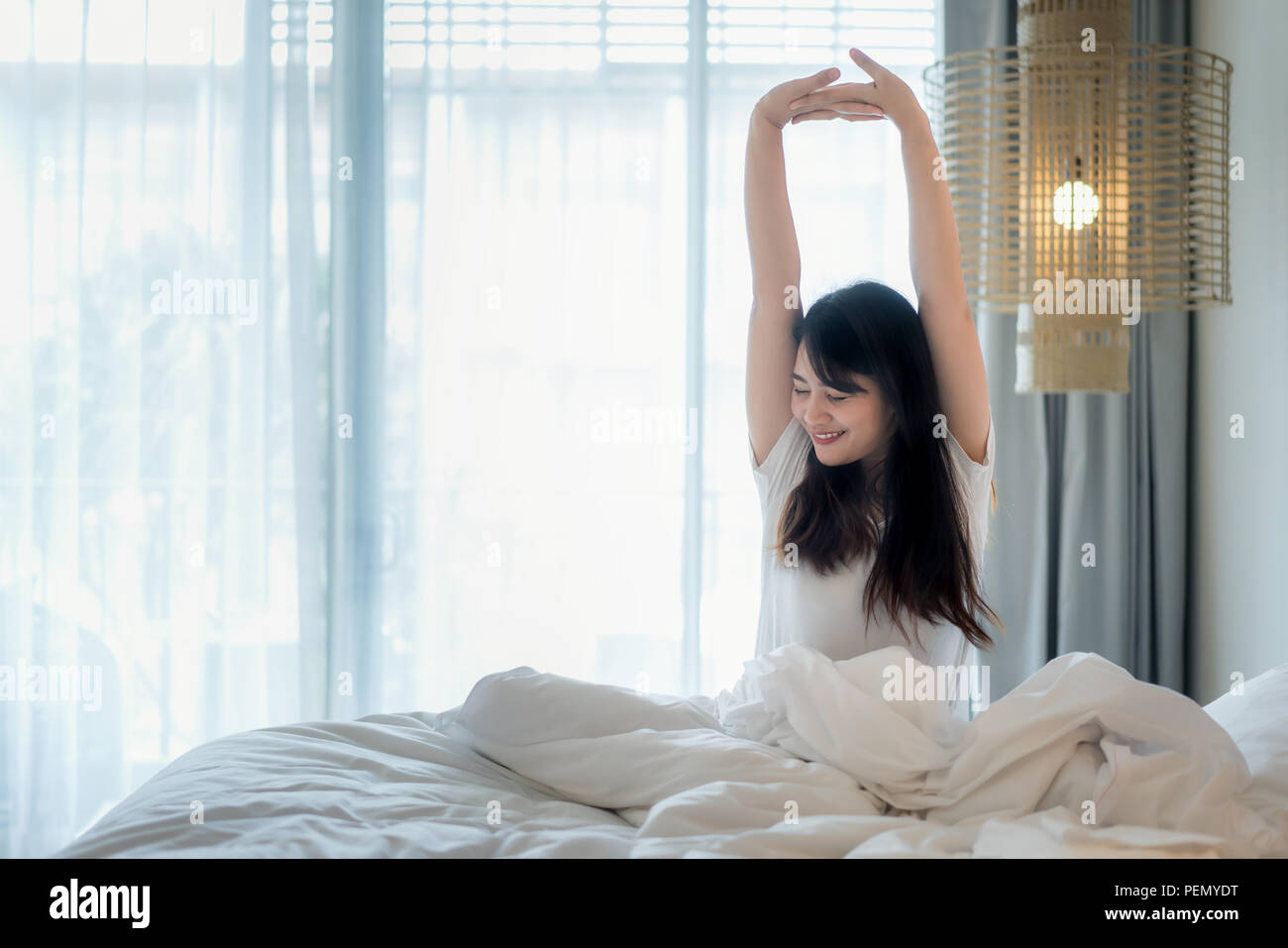 Asiatische Frau Stretching im Bett nach dem Aufwachen im Schlafzimmer zu Hause. Stockfoto