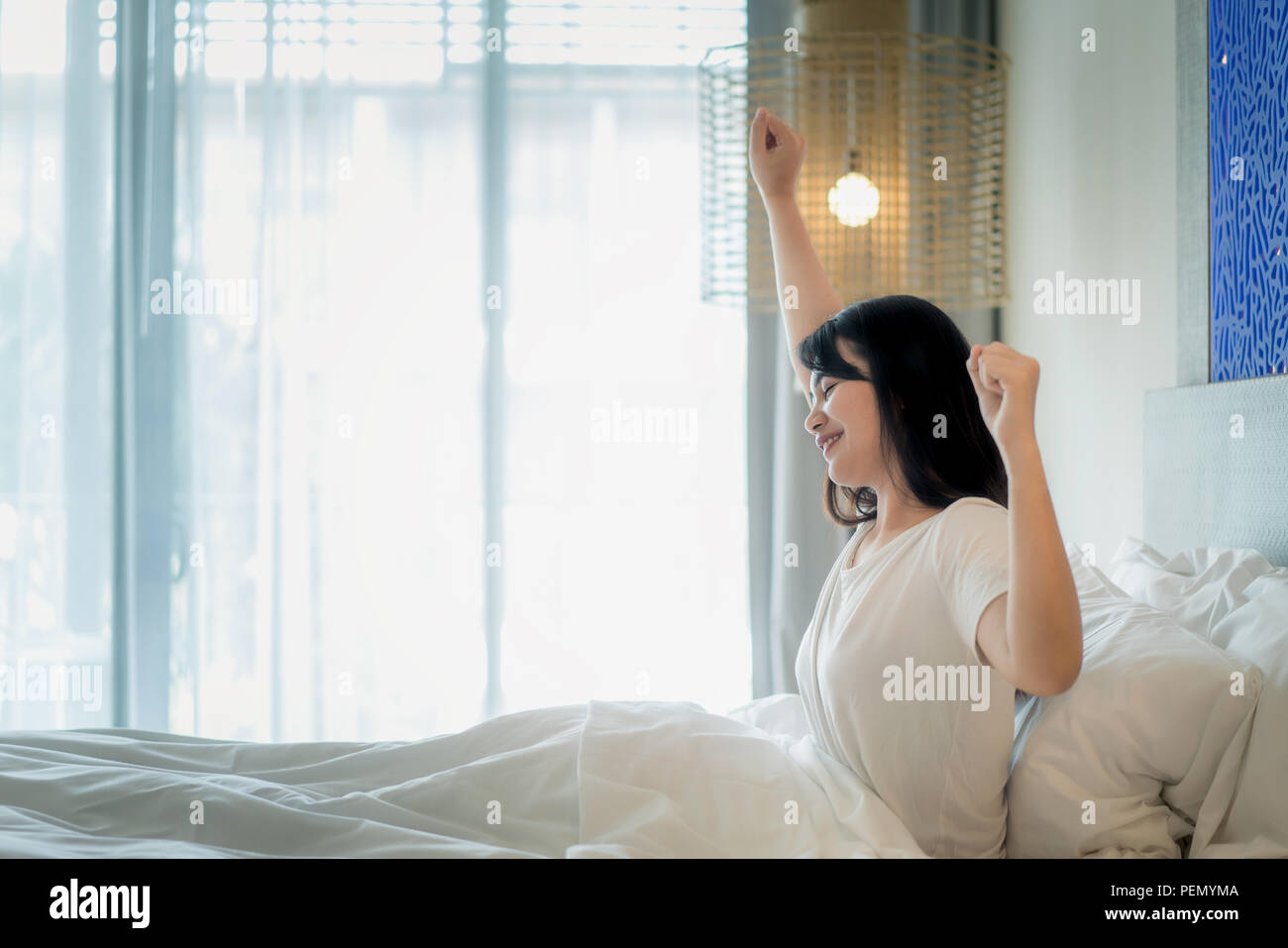 Asiatische Frau Stretching im Bett nach dem Aufwachen im Schlafzimmer zu Hause. Stockfoto