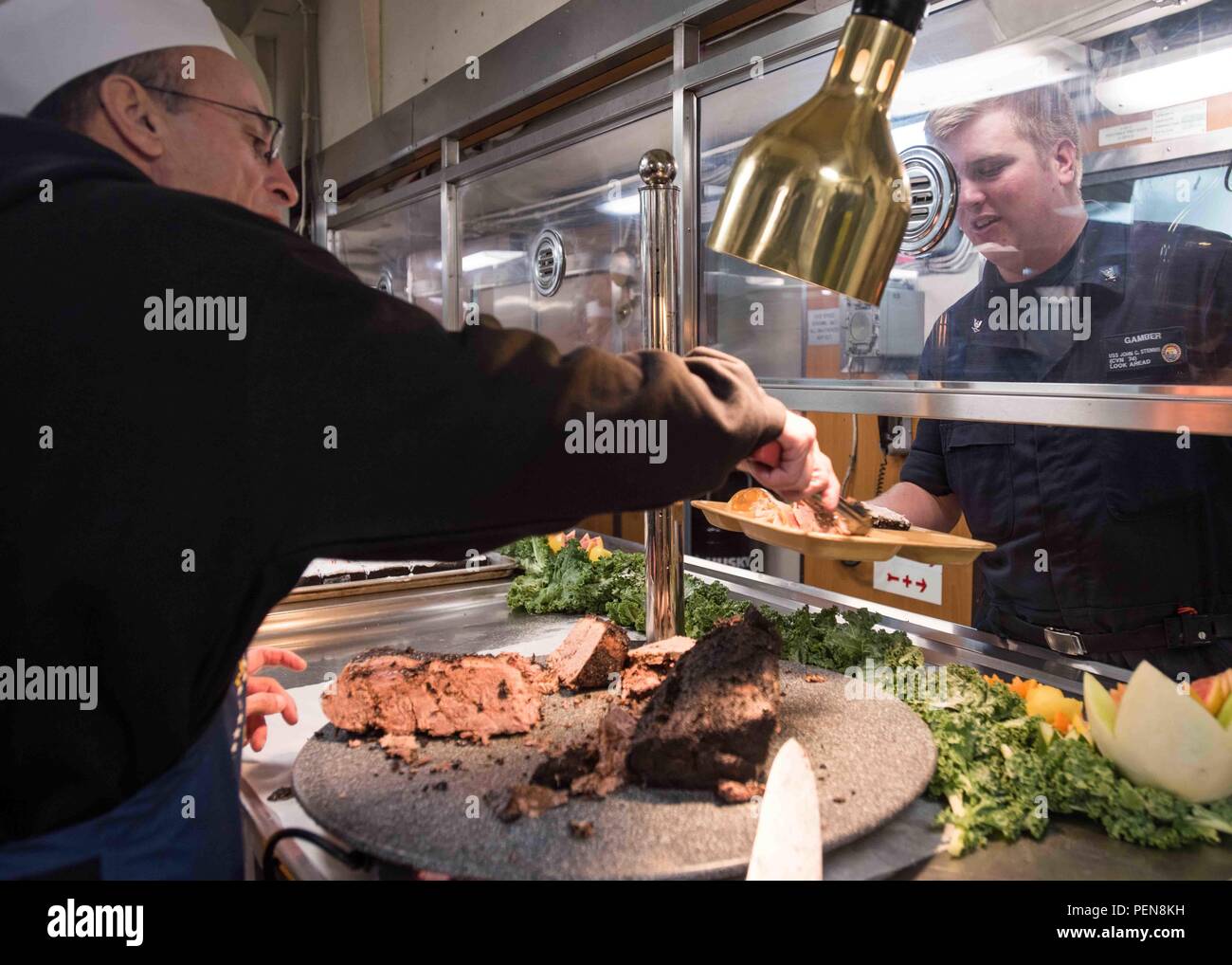 151225-N-ZA 585-024 BREMERTON Washington (31. 25, 2015) - Ernie Samaras, von Seattle, dient der Machinist Mate 3. Klasse Matthew Gamber, aus New Canaan, Anschl. Prime Rib im aft galley an Bord der USS John C Stennis (CVN 74). Stennis "Crew ist derzeit in Port Training für zukünftige Bereitstellungen. (U.S. Marine Foto von Mass Communication Specialist 2. Klasse Patrick Enright/Freigegeben) Stockfoto