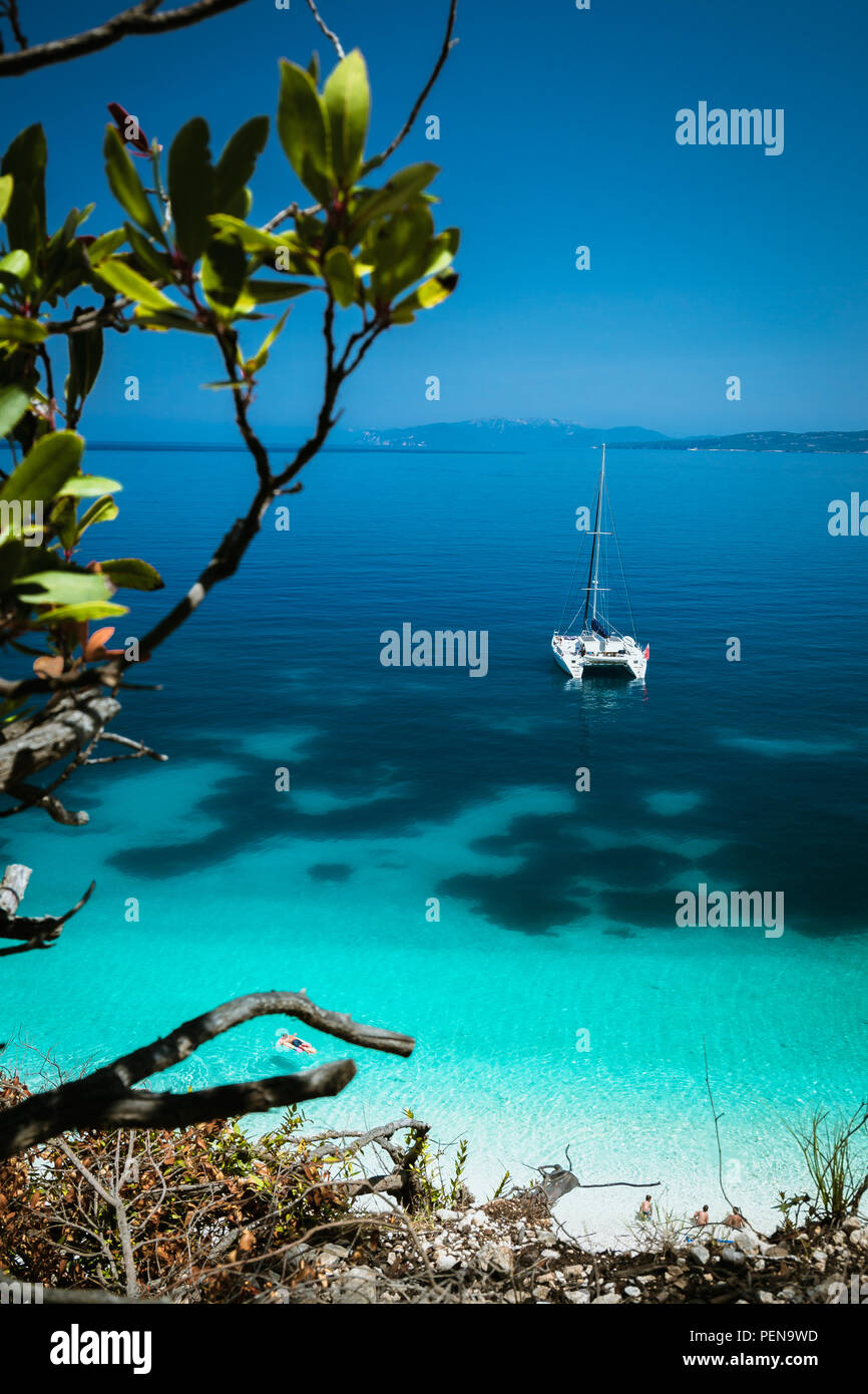 Weißen Katamaran Yacht am azurblauen Oberfläche Anker mit dunklem in ruhigen blauen Lagune. Nicht erkennbare Touristen auf in Wasser, in der Nähe des Strandes Luftmatratze entspannen Stockfoto