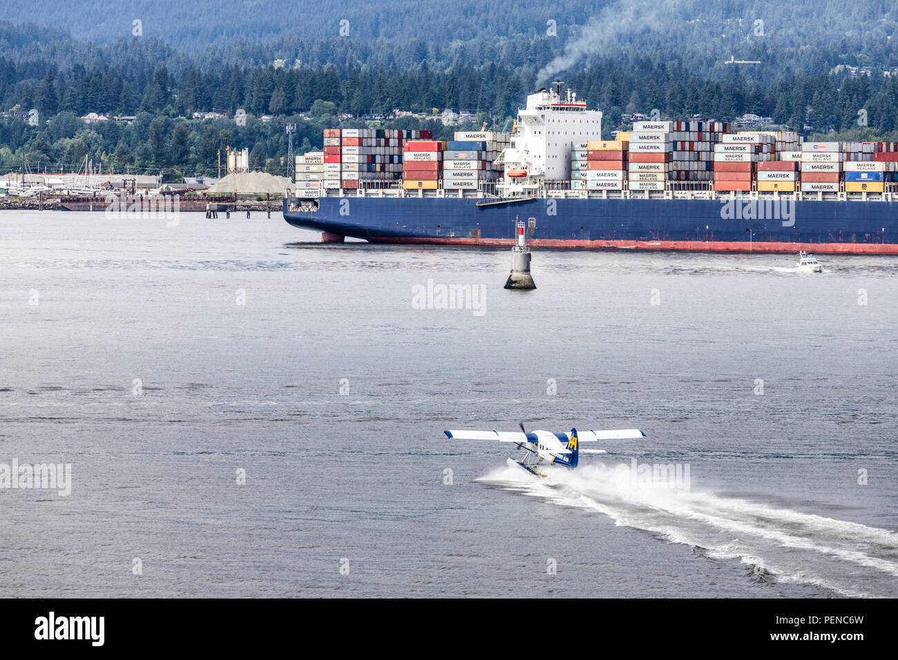 Ein Tourist mit dem Wasserflugzeug in ganz in der Nähe der Container schiff Seamax Stratford im Hafen von Vancouver, British Columbia, Kanada Stockfoto