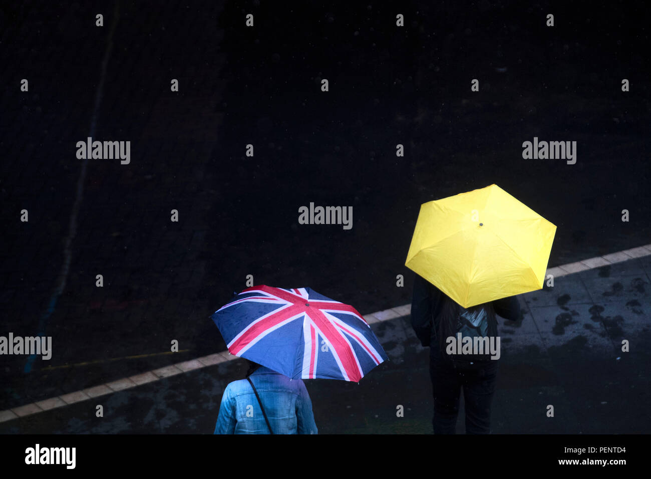 Die Menschen halten Regenschirme im Regen vor Wembley Park Station im Norden von London. Stockfoto