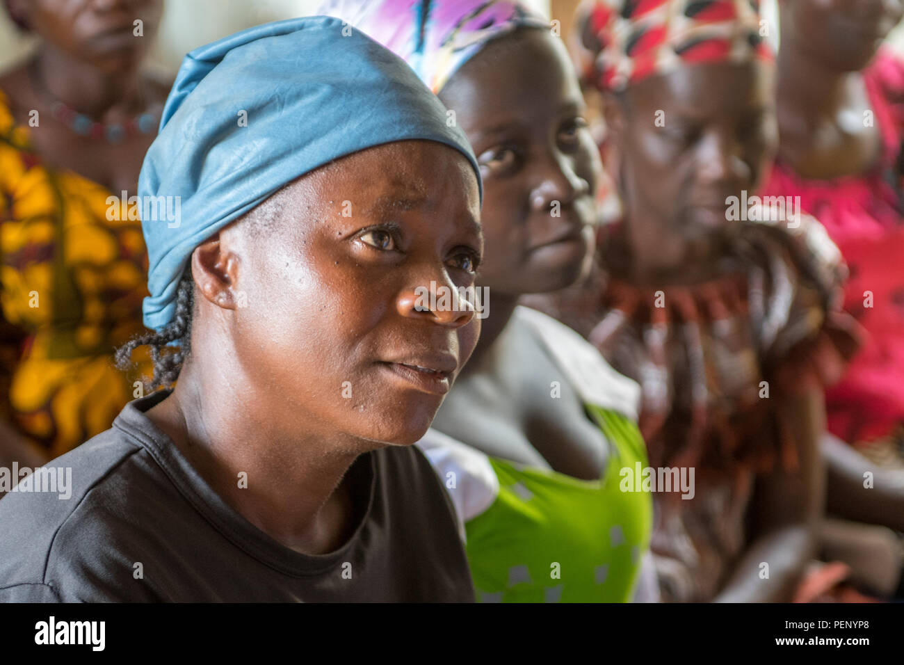 Eine Frau hört mit einem fokussierten Ausdruck zu einer Kirche Nachricht in Ganta, Liberia Stockfoto