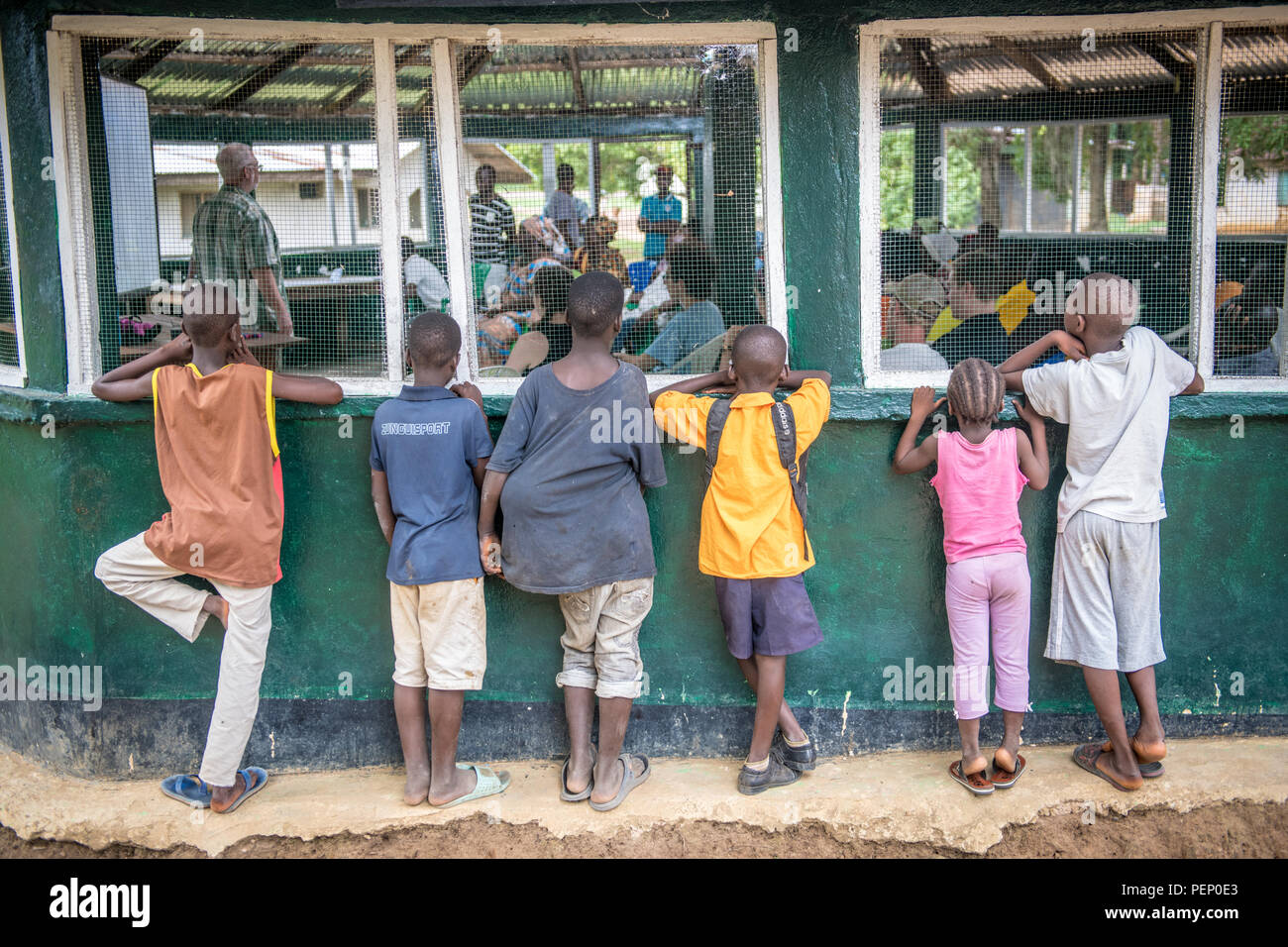 Kinder peer durch ein Fenster auf eine Präsentation in Ganta, Liberia Stockfoto