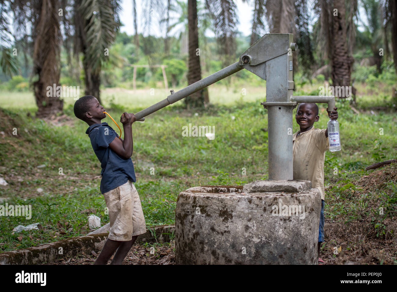 Junge Kinder Pumpe Wasser aus einem Brunnen in Ganta, Liberia Stockfoto