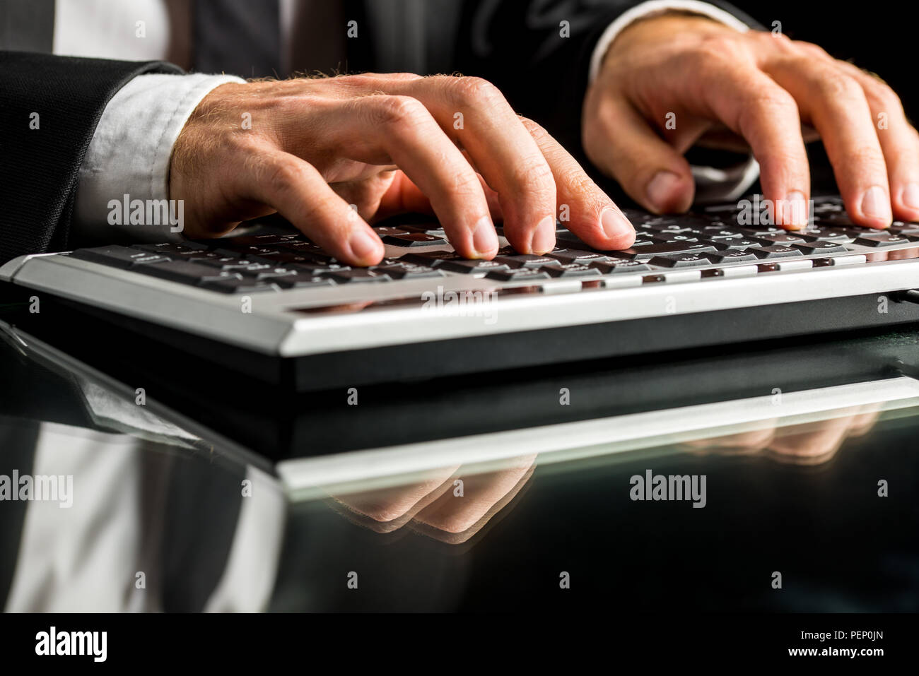 Hände eines Geschäftsmanns, der auf dem Computer durch Maschinenschreiben auf der Tastatur, auf ein Glas Schreibtisch mit Reflexion. Stockfoto