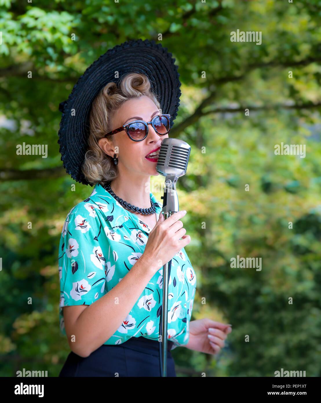 Die Sängerin Jayne Darling singt vor dem Vintage-Mikrofon draußen und unterhält die Menschenmassen im Crich Tramway Village, Veranstaltung 1940s. Stockfoto