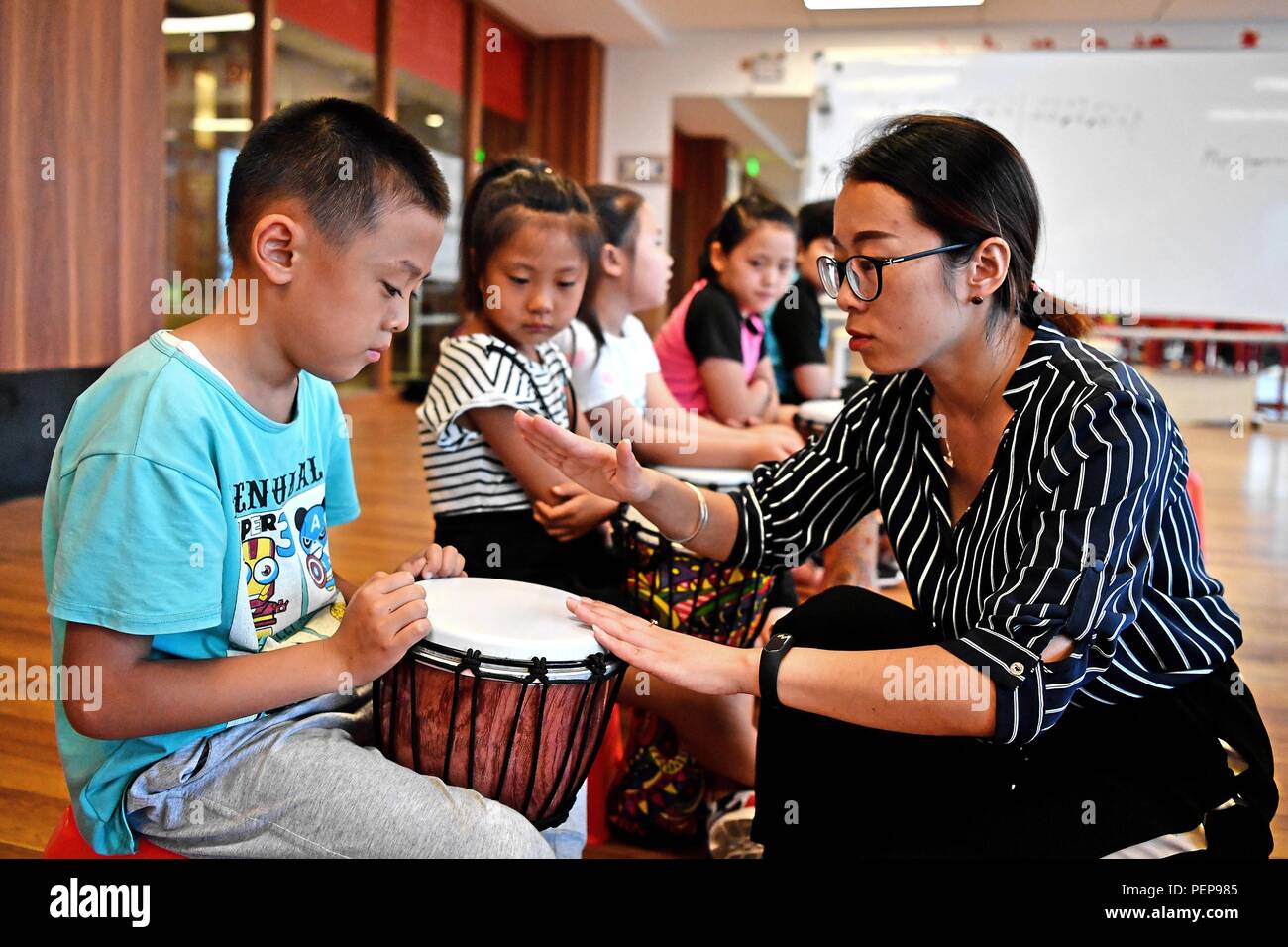 Langfang, Provinz Hebei Provinz Chinas. 16 Aug, 2018. Kunstlehrerin (R) lehrt Kinder spielen afrikanische an Anci Kulturzentrum in der Anci Bezirk Langfang Stadt drum, im Norden der chinesischen Provinz Hebei, Aug 16., 2018. Die Kinder besuchen die freie Kunst Klassen ihre Sommerferien zu bereichern. Credit: Liu Xuemin/Xinhua/Alamy leben Nachrichten Stockfoto