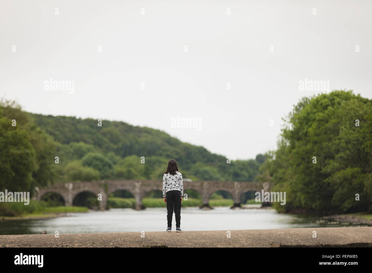 Stehendes Mädchen auf umgebende Mauer in der Nähe des Riverside Stockfoto