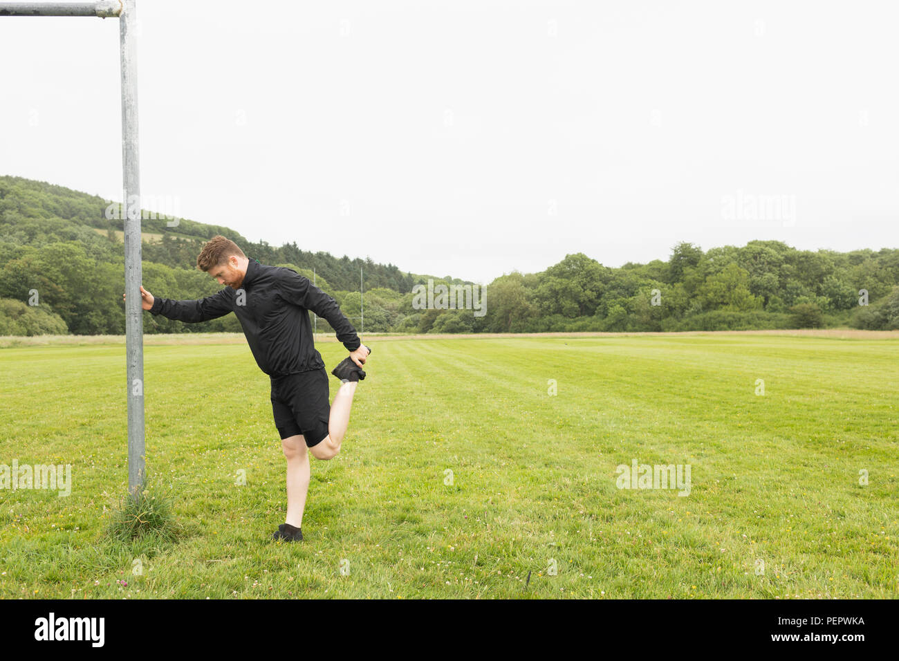 Mann zu tun Stretching an der grünen Landschaft Stockfoto