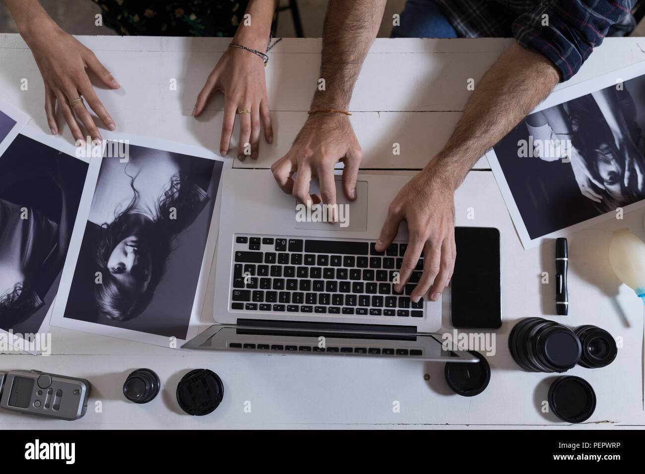 Männliche und weibliche Fotografen mit Laptop in Photo Studio Stockfoto