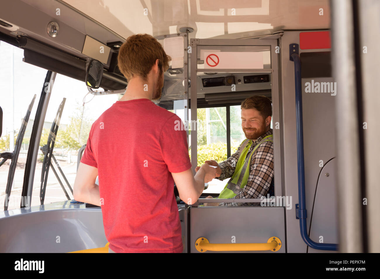 Männliche Pendler unter Ticket vom Fahrer in Bus Stockfoto