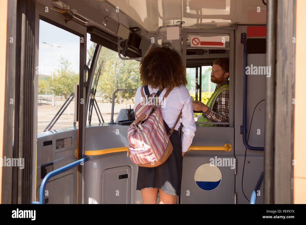 Weibliche Pendler unter Ticket vom Treiber im modernen Bus Stockfoto