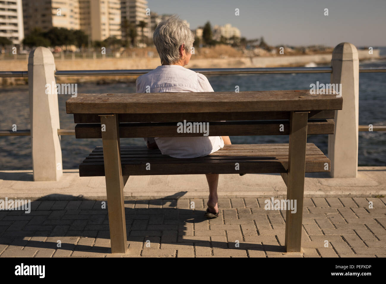 Ältere Frau sitzt auf der Bank am Meer an der Promenade Stockfoto