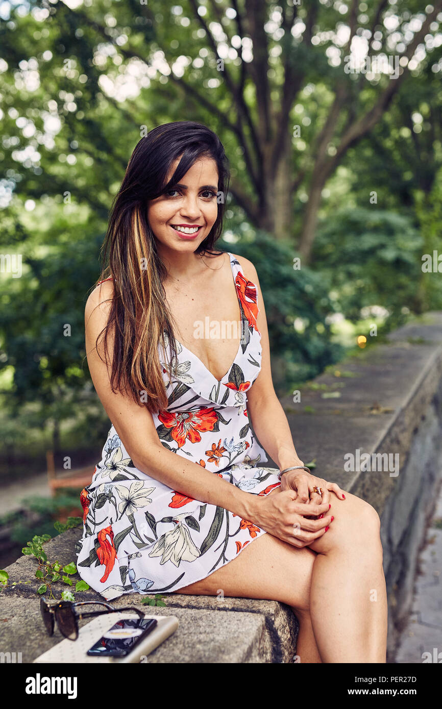 Schöne Latina, Hispanic Frau sitzt auf einem Stein Wand Stockfoto