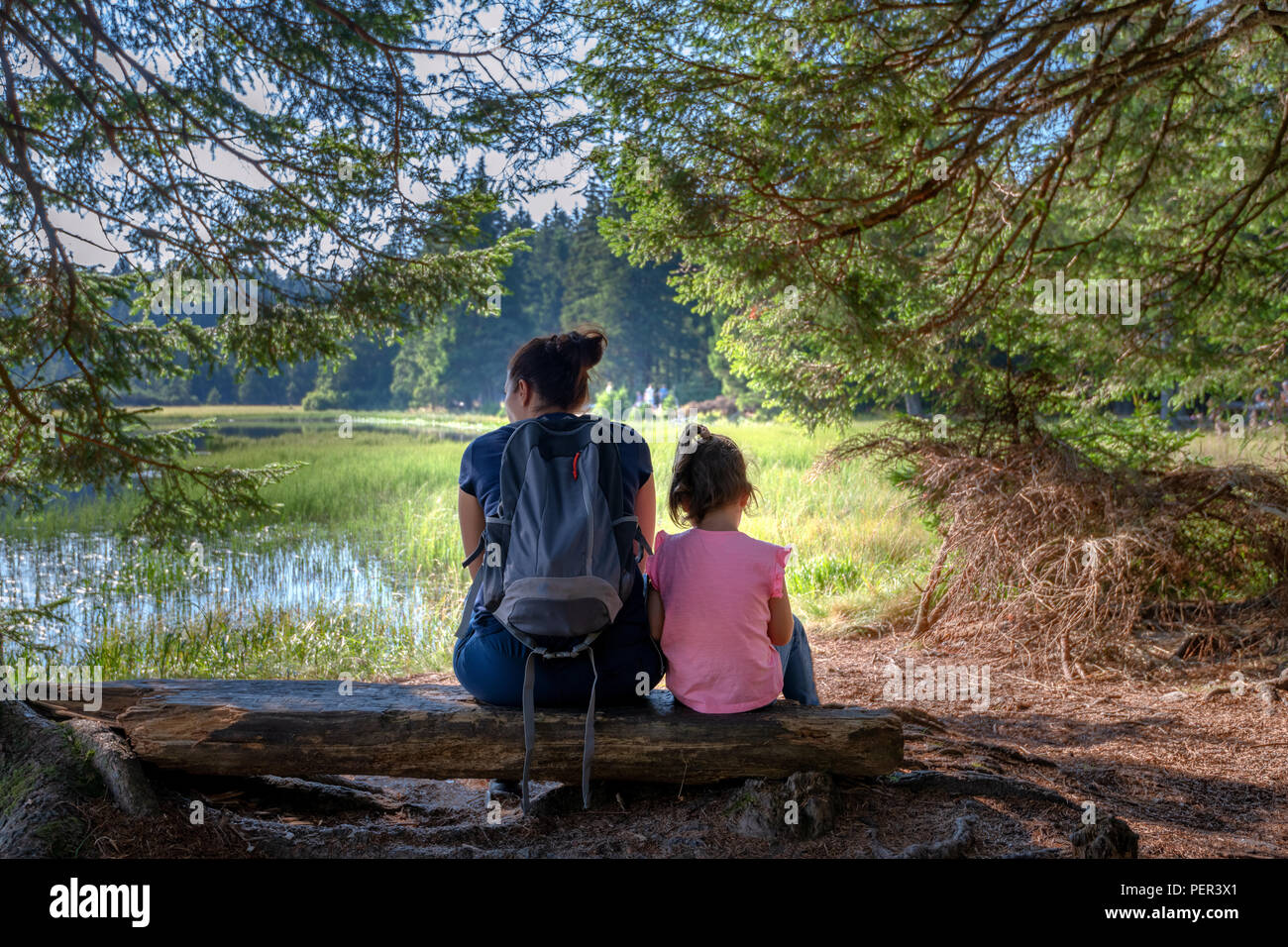 Mutter und Tochter sitzt auf der Bank in der Nähe von Mountain Lake, weg zeigt, Familie outdoor Wandern in der Natur, die Liebe zwischen Müttern und Töchtern Stockfoto
