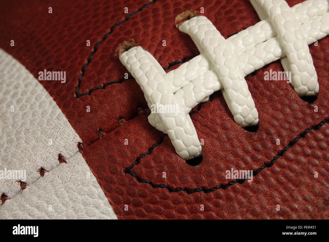 Ein American Football Spiel Ball ist zu sehen in der Nähe, mit dem Blick auf die Schnürsenkel, Heften, und weiß, lackiert Streifen fokussiert. Stockfoto