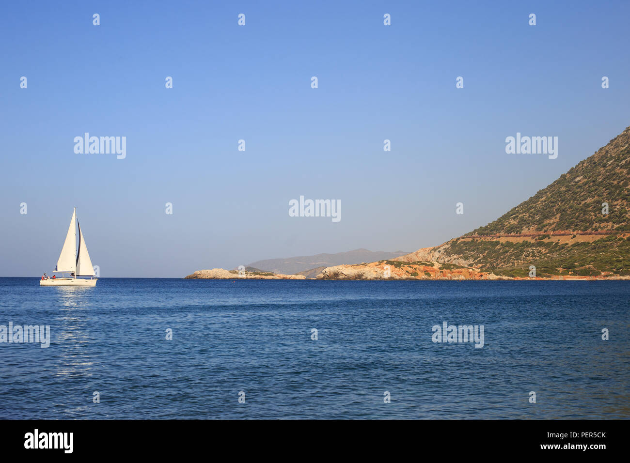 Weißes Segelboot auf dem offenen Meer. Segelyacht in das offene Meer mit den Bergen im Hintergrund. Stockfoto