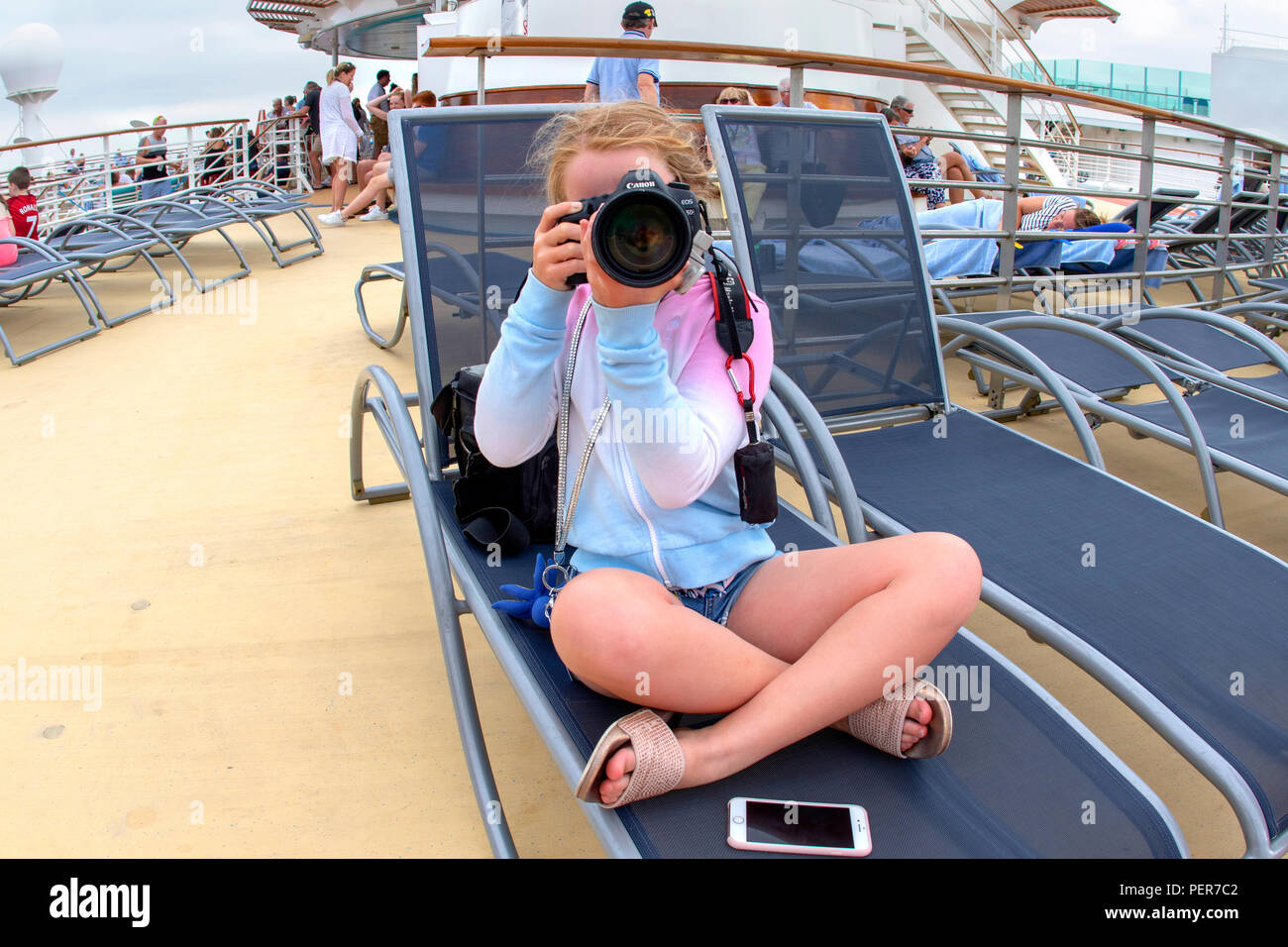 Junge Mädchen fotografieren während saß auf einem Liegestuhl auf einem Kreuzfahrtschiff Stockfoto