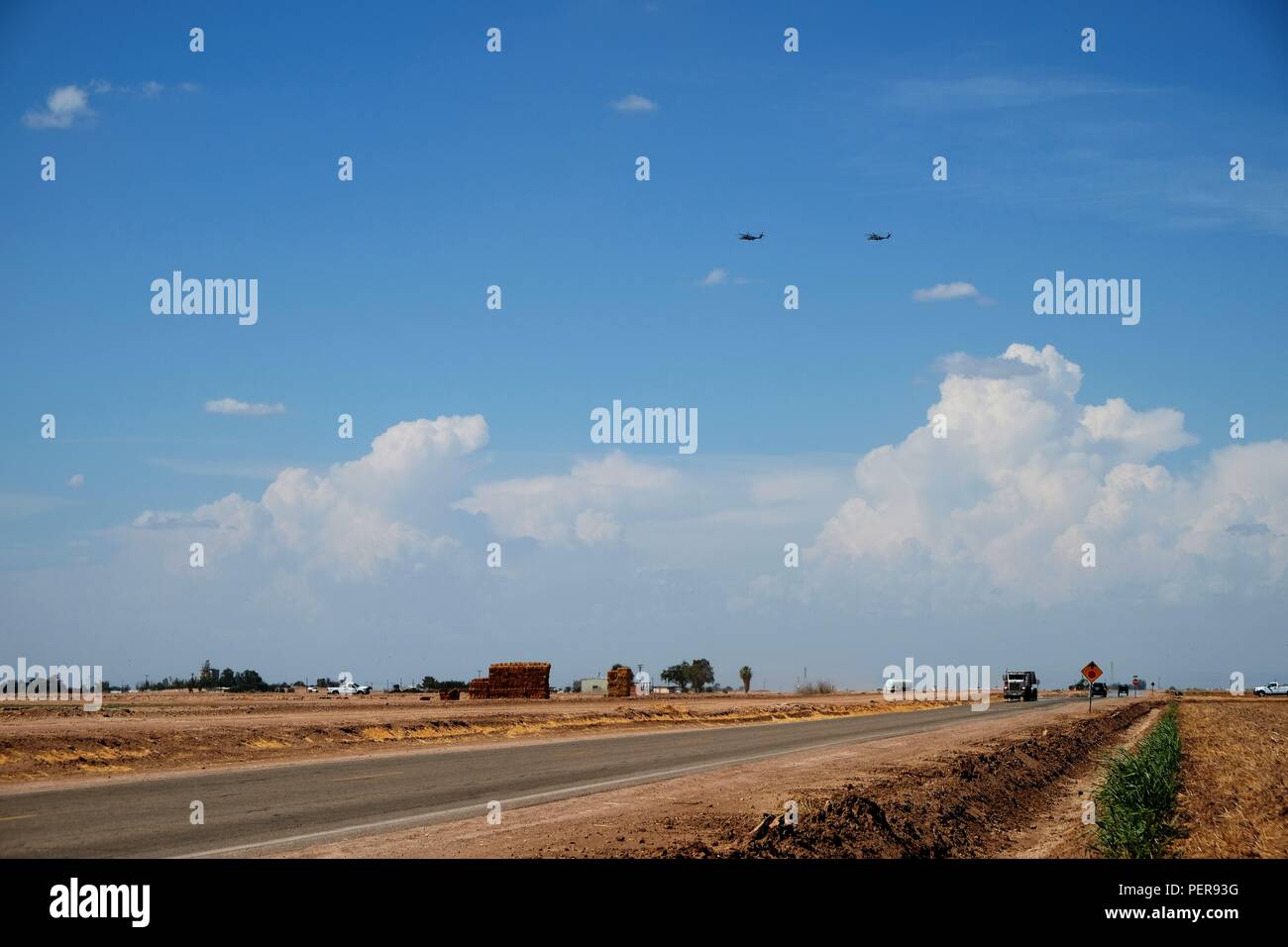 Bowker Rd. nach Norden außerhalb von Calexico, Kalifornien durch landwirtschaftliche Felder und zwei militärische Hubschrauber am Himmel umgeben, Imperial County. Stockfoto