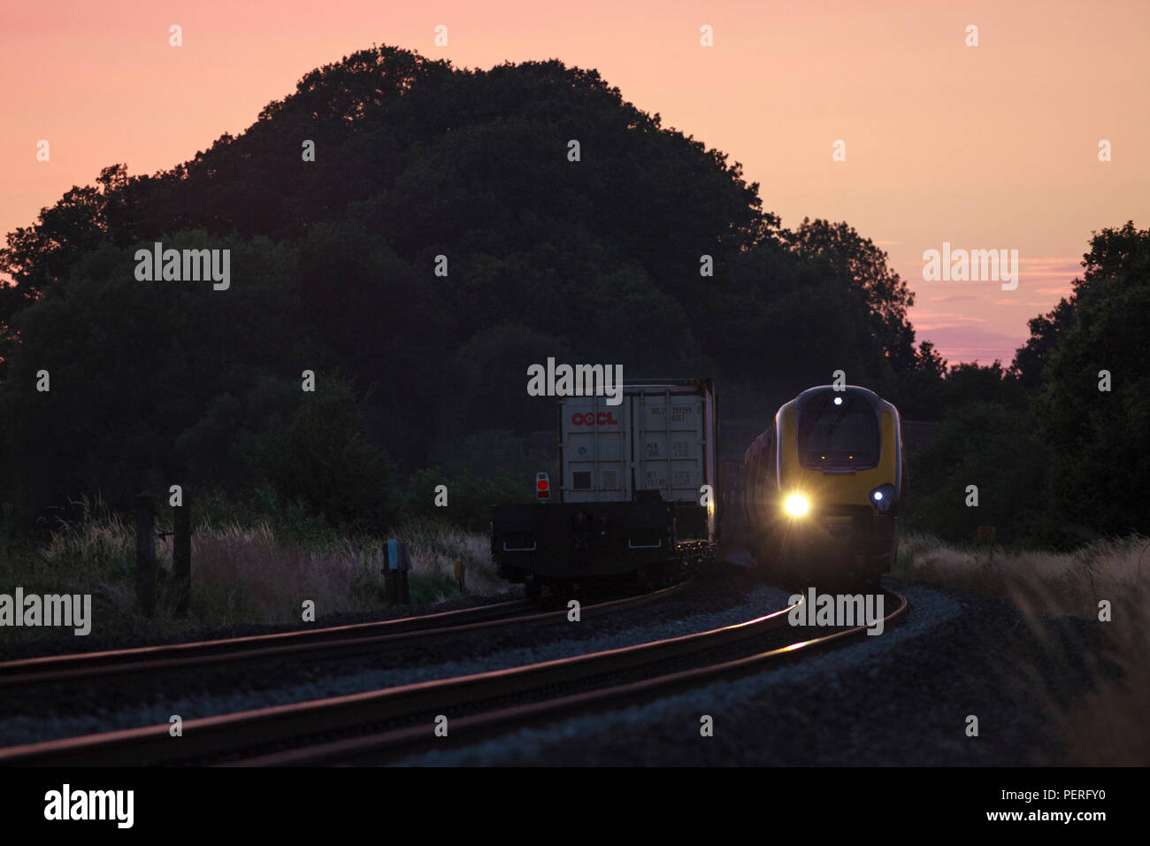 Länderübergreifende Züge Voyager Passagier Zug passiert ein Freightliner intermodalen Container Freight Train Funkeln in den Sonnenuntergang im Cherwell Valley UK Stockfoto