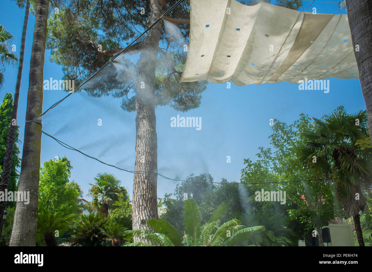 Markise und Sprinkler spritzt verdampft Wasser bei öffentlichen Park. Geräte für die Kühlung der heißen Sommer Temperatur in Spanien im Freien Stockfoto