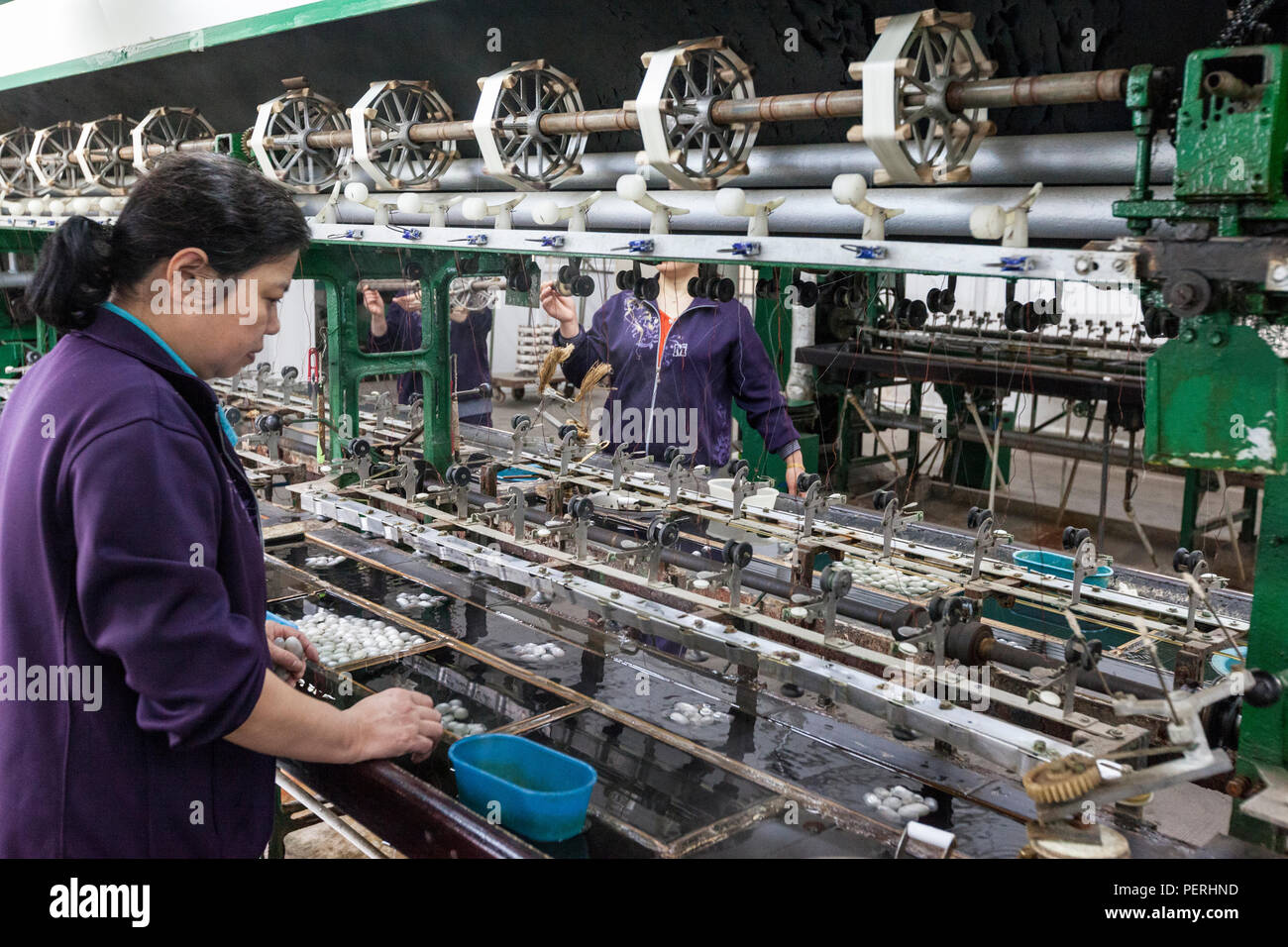 Suzhou, Jiangsu, China. Seidenfabrik. Waschen Kokons, dann Abrollen auf die Oberleitung Rollen. Stockfoto