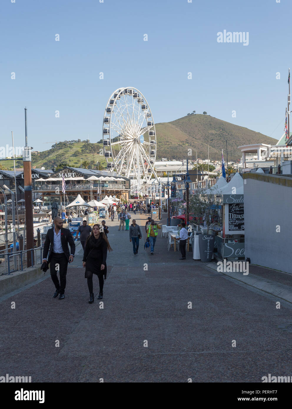 V&A Waterfront in Kapstadt, Südafrika ist eine touristische Attraktion oder Ziel mit dem Signal Hill im Hintergrund und die Menschen flanieren Stockfoto