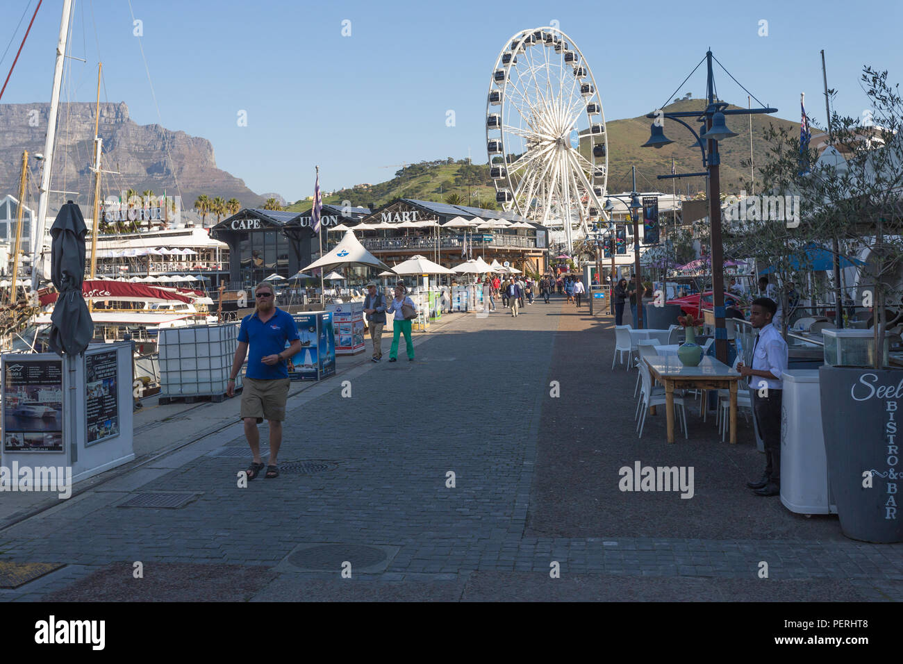V&A Waterfront in Kapstadt, Südafrika mit dem Tafelberg und Signal Hill in den Hintergrund und die Menschen in den Vordergrund bummeln Stockfoto