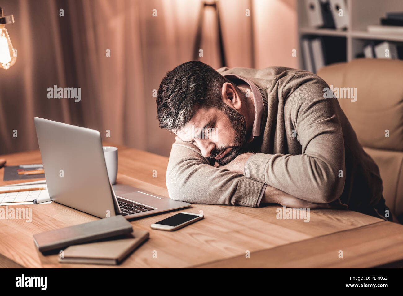 Müde Geschäftsmann auf dem Schreibtisch vor dem Laptop Stockfoto