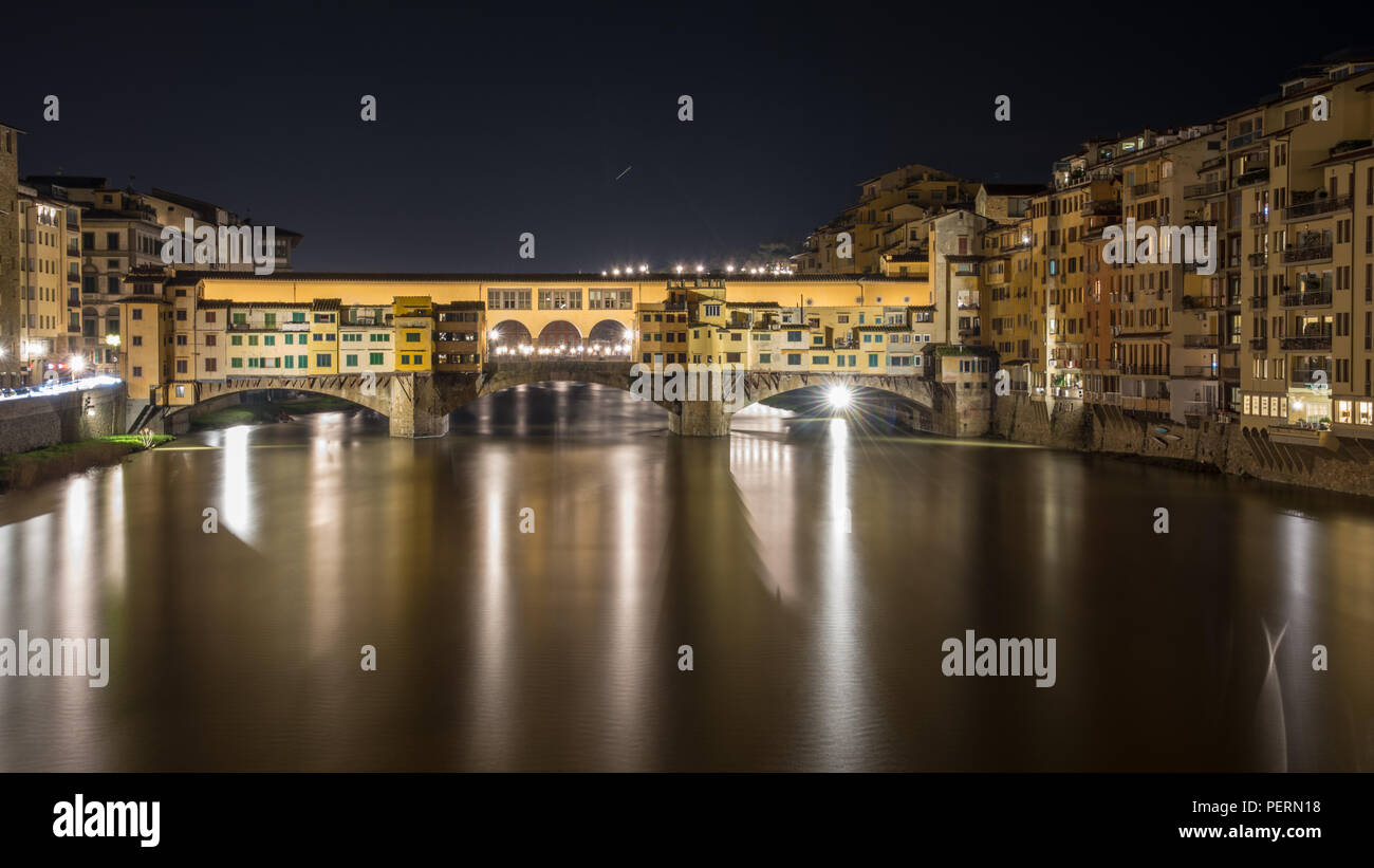 Florenz, Italien - 21. März 2018: Der Fluss Arno fließt unterhalb der historischen Brücke Ponte Vecchio in Florenz bei Nacht, mit jupiter rising Overhead. Stockfoto