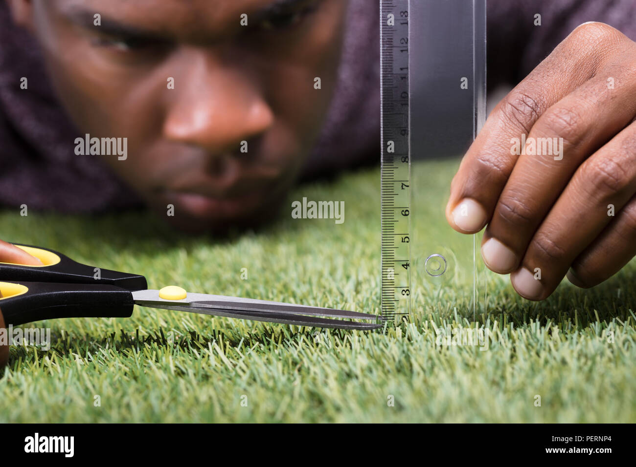 Nahaufnahme eines Mannes Schneiden grüne Gras Gemessen mit Lineal Stockfoto